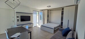 Ein modernes Wohnzimmer mit Flachbildfernseher, einem Esstisch und einer Couch.