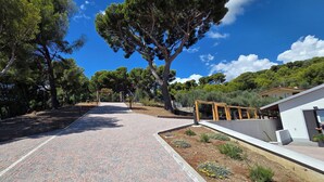 A paved pathway leading to a gated entrance, surrounded by trees and a white building with a sloped roof. - Nice apartment in villa with WIFI, A/C, TV, patio and panoramic view, close to Imperia (San Bartolomeo Al Mare)