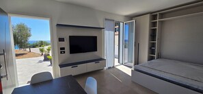 Una habitación moderna con televisión de pantalla plana, una mesa de comedor y un sofá.