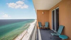 Un balcone con vista su una spiaggia e l'oceano. Sul balcone ci sono due sedie e un tavolo.