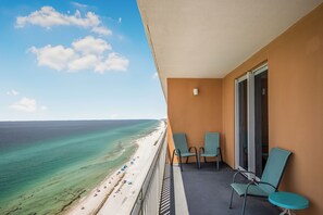 A balcony with a view of a beach and ocean. There are two chairs and a table on the balcony. - 19th Floor Gulf Views | 2 King Suites | Splash Resort East Tower (Panama City Beach)