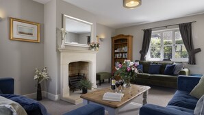 Ein Wohnzimmer mit Kamin, Bücherregal, einer Couch und einem Couchtisch.
