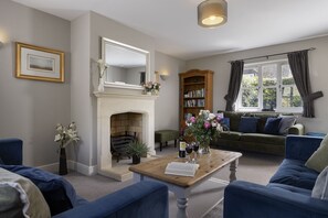 Ein Wohnzimmer mit Kamin, Bücherregal, einer Couch und einem Couchtisch.
