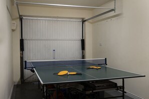A ping pong table with paddles and a net in a room with a white door and walls. - Birch House -  a cottage that sleeps 8 guests  in 4 bedrooms (Stow-on-the-Wold)