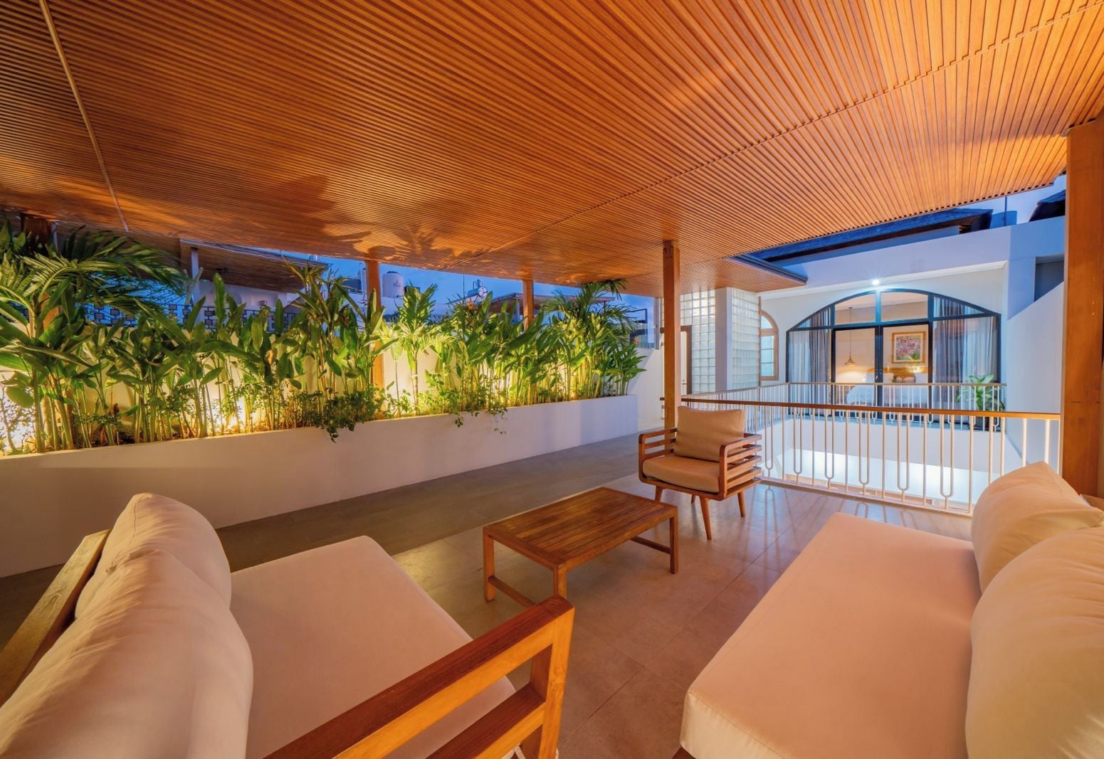A modern outdoor seating area with a wooden ceiling, a sofa, a chair, and a table.