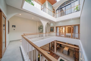 Ein mehrgeschossiges Interieur mit einer zentralen Treppe, Holzgeländern und einem Essbereich.