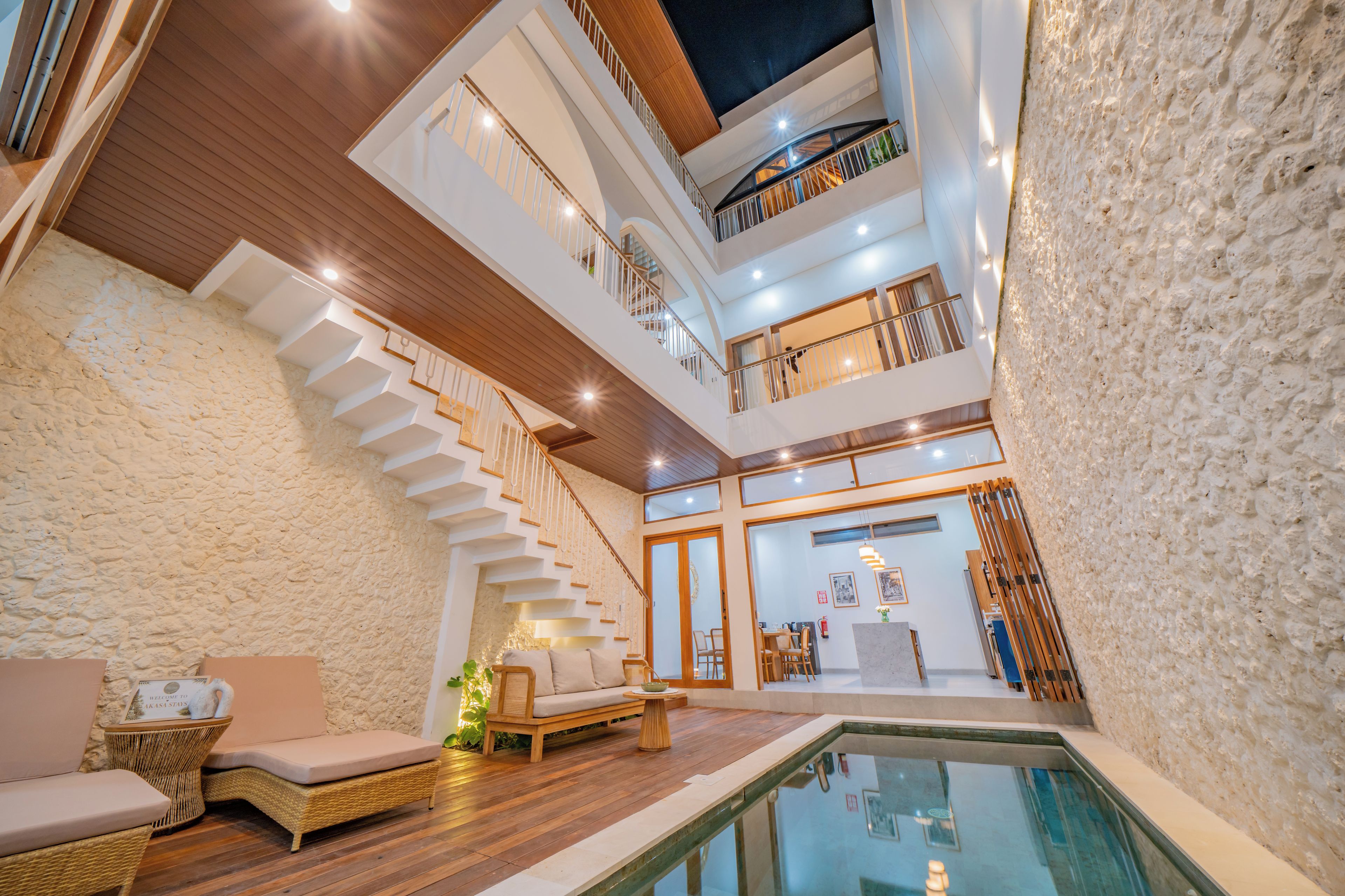 Un interior de varios niveles con piscina, suelo de madera y una escalera.