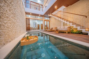 A modern indoor pool area with a clear glass floor, a wooden deck, and a staircase leading to an upper level. - 3BR Umalas Villa • Pool & Rooftop Terrace • Scooter & Restaurant discounts (Kuta Utara)