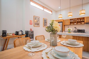 Een moderne keuken met een eethoek, met een houten tafel gedekt voor vier personen, een koffieapparaat en een waterdispenser.