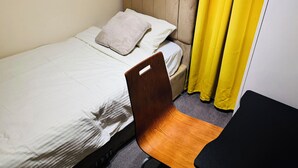A single bed with a headboard, a pillow, and a chair in a room with a yellow curtain. - Room-home for Contractors and Tourists (Salford)