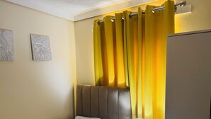 A hotel room with a bed, a bedside lamp, a curtain, and two wall art pieces. - Room-home for Contractors and Tourists (Salford)