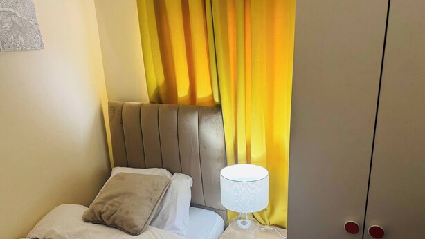 A bedroom with a bed, a nightstand with a lamp, and a wardrobe. - Room-home for Contractors and Tourists (Salford)