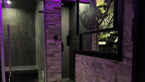 A modern bathroom with a glass shower enclosure, a stone wall, and a decorative tree cutout. - Cozy 1-bedroom house in fantastic Rosult with AC (Rosult)