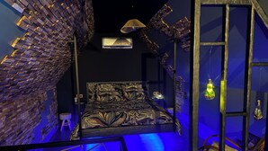A room with a bed, a chair, a hanging light fixture, and a wall with a brick pattern. - Cozy 1-bedroom house in fantastic Rosult with AC (Rosult)