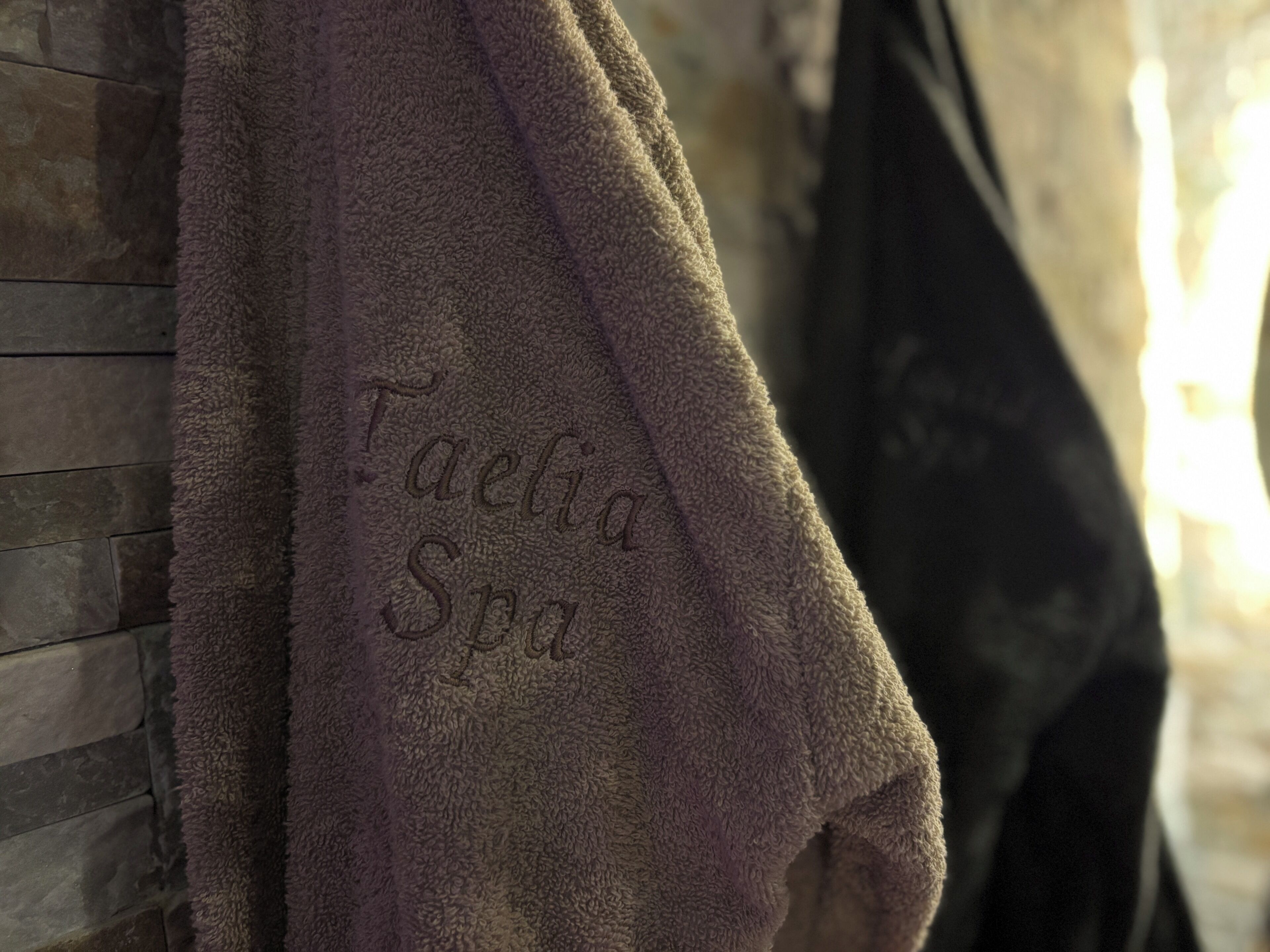 Une serviette ornée d’un motif en relief représentant le texte « Taelia Spa », accrochée à un mur.