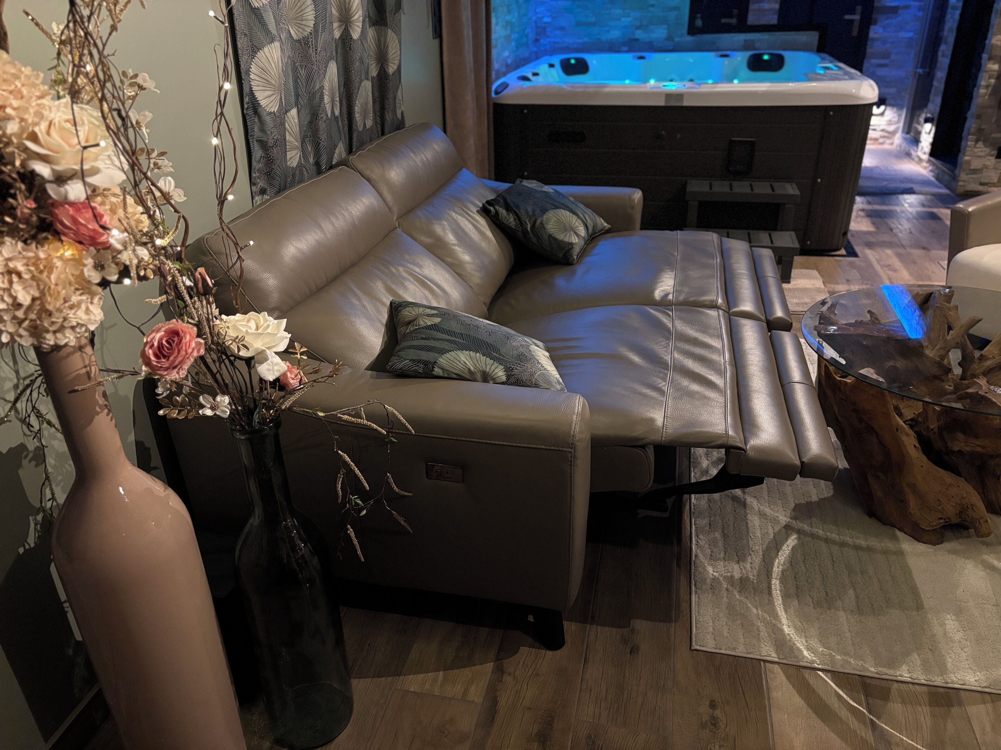 Un salon moderne avec un canapé en cuir, une table basse en verre et un vase décoratif orné de fleurs.