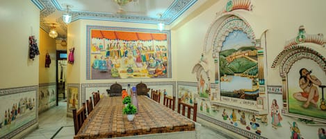 A traditional room with a large mural, a dining table, and a chandelier.