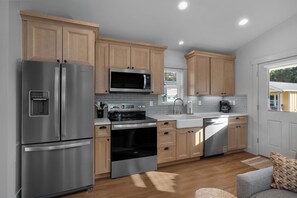 A modern kitchen with stainless steel appliances, wooden cabinets, and a built-in microwave. - Seabrook Hazelwood Cottage | Pet Friendly, Kitchen | 1BR, Sleeps 2, Fernwood (Pacific Beach)
