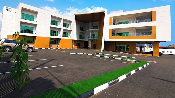 Un edificio moderno con estacionamiento, varios pisos y una zona verde.