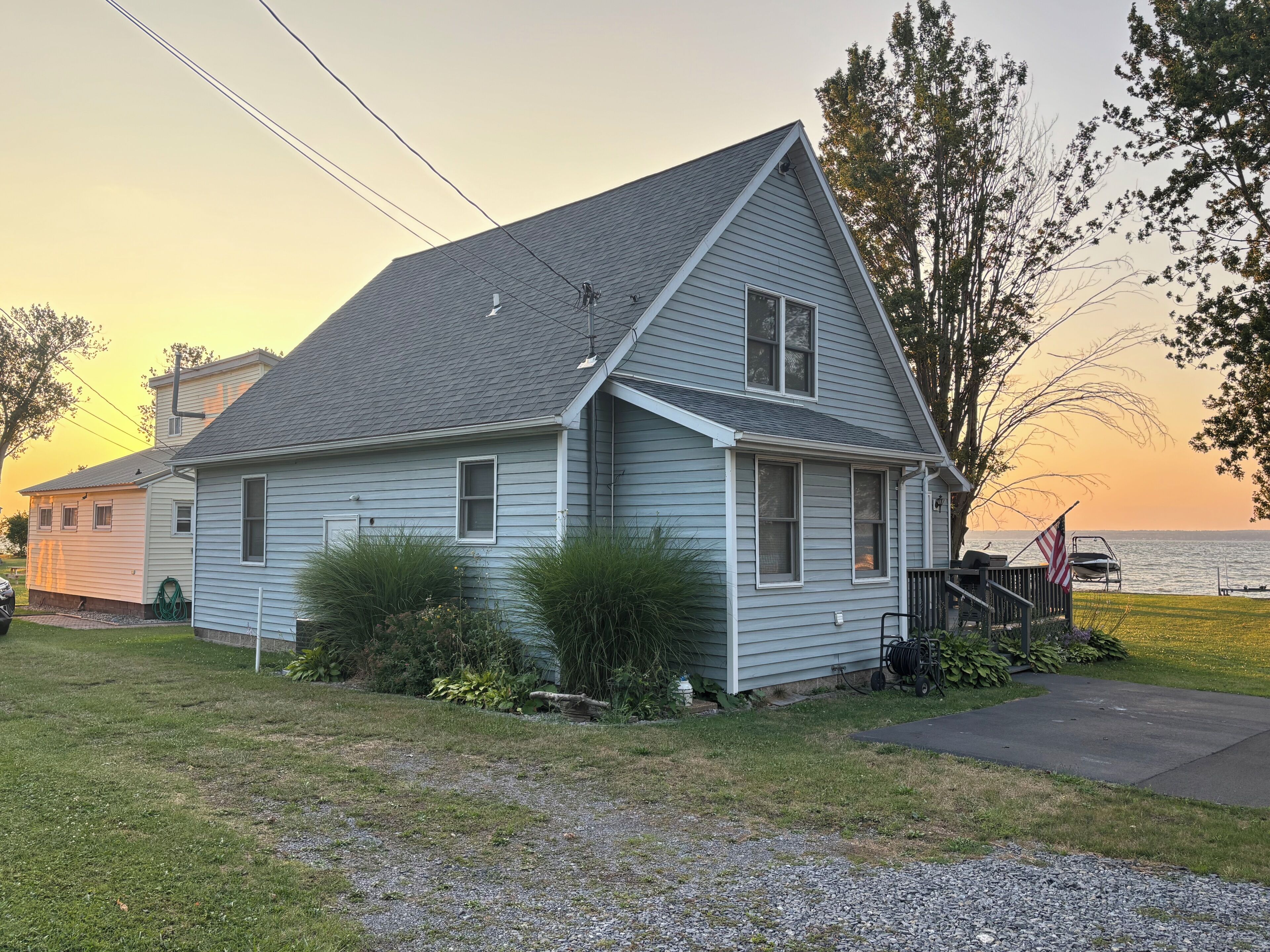 A single-story house with a gabled roof, a front porch, and a view of the water.