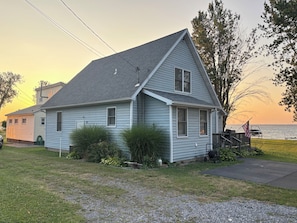 A single-story house with a gabled roof, a front porch, and a view of the water.