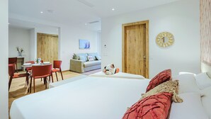 Ett modernt hotellrum med en stor säng, en matplats och ett vardagsrum.