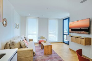 Ein modernes Wohnzimmer mit einer Couch, einem Couchtisch und einem an der Wand befestigten Fernseher.