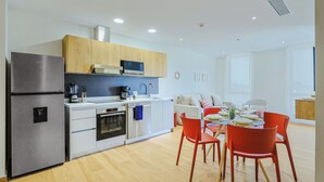 Cocina moderna equipada con refrigerador, horno, microondas y cafetera.