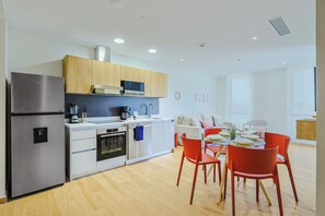 Eine moderne Küche mit Kühlschrank, Backofen, Mikrowelle und Kaffeemaschine.