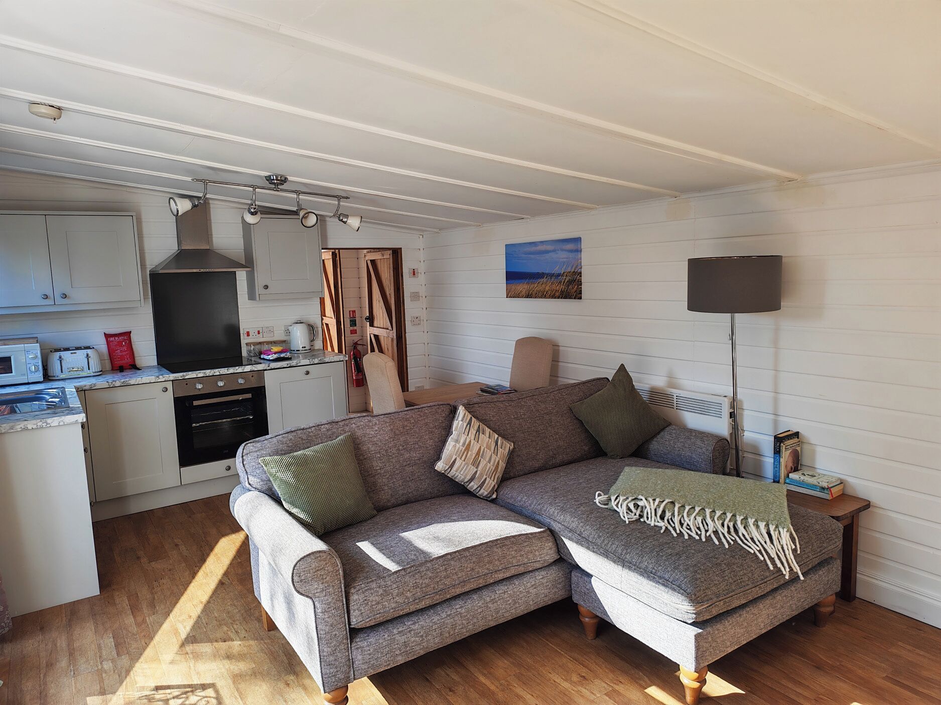 A cozy living room with a sectional sofa and a kitchen area with a stove and microwave.