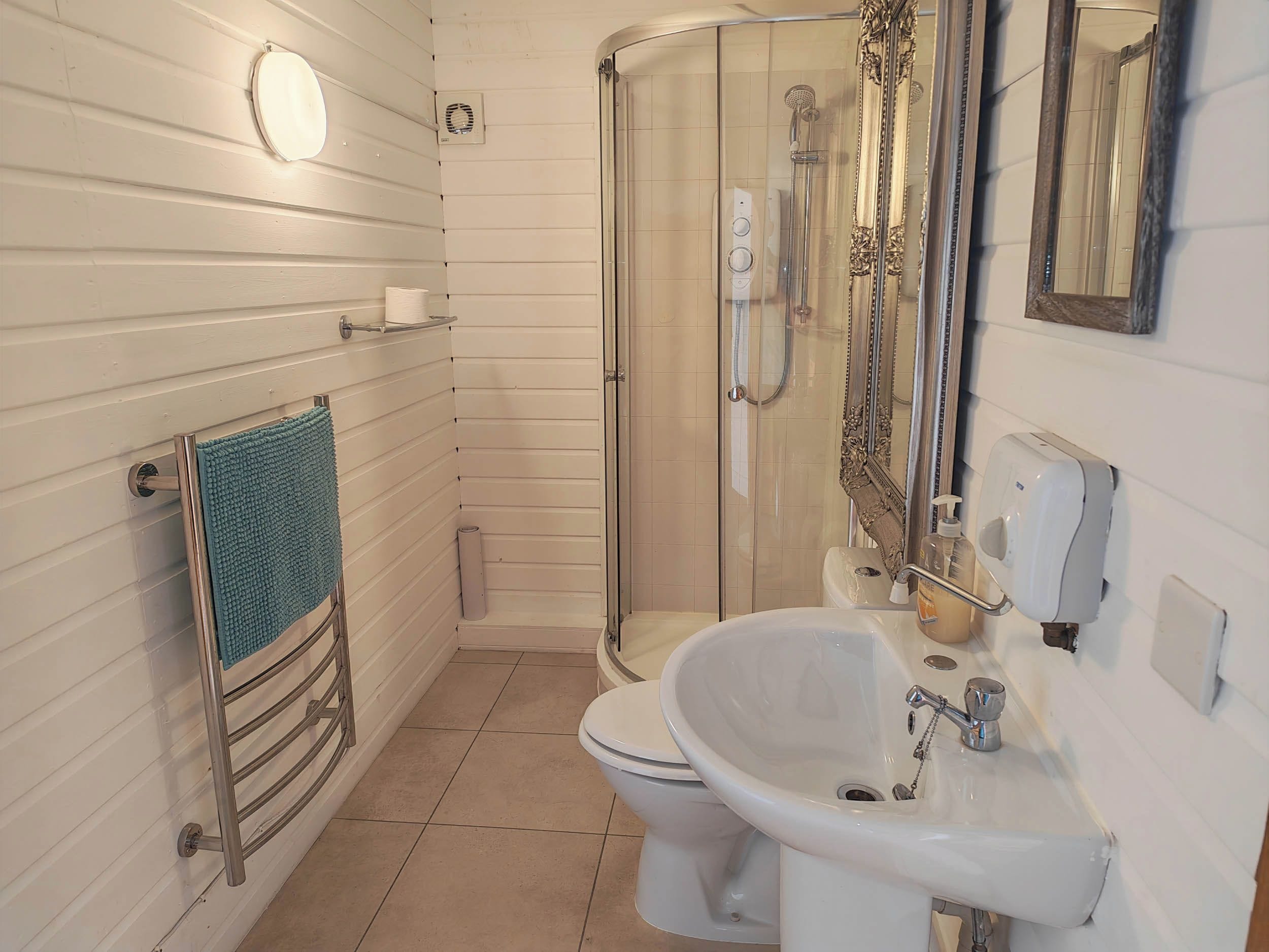 Un baño con inodoro, lavamanos, ducha y toallero.