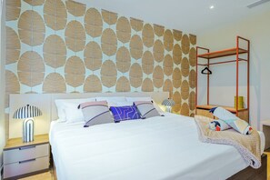 A hotel room with a large bed, a bedside table, a hanging light, and a wardrobe with a mirror. - Bonsai 1BR Suite-Wood Heaven 305 (Noord)