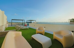 Terraço no topo com piscina, espreguiçadeiras e área de estar coberta.