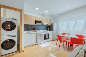 Una cuina moderna amb electrodomèstics integrats, una zona de menjador amb cadires vermelles i una finestra gran que proporciona llum natural.