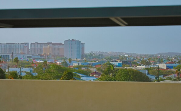 Vista urbana com edifícios residenciais, áreas verdes e céu claro.