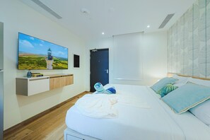 Ein Schlafzimmer mit einem Bett, einem an der Wand befestigten Fernseher, einem Kleiderschrank und einer Tür.