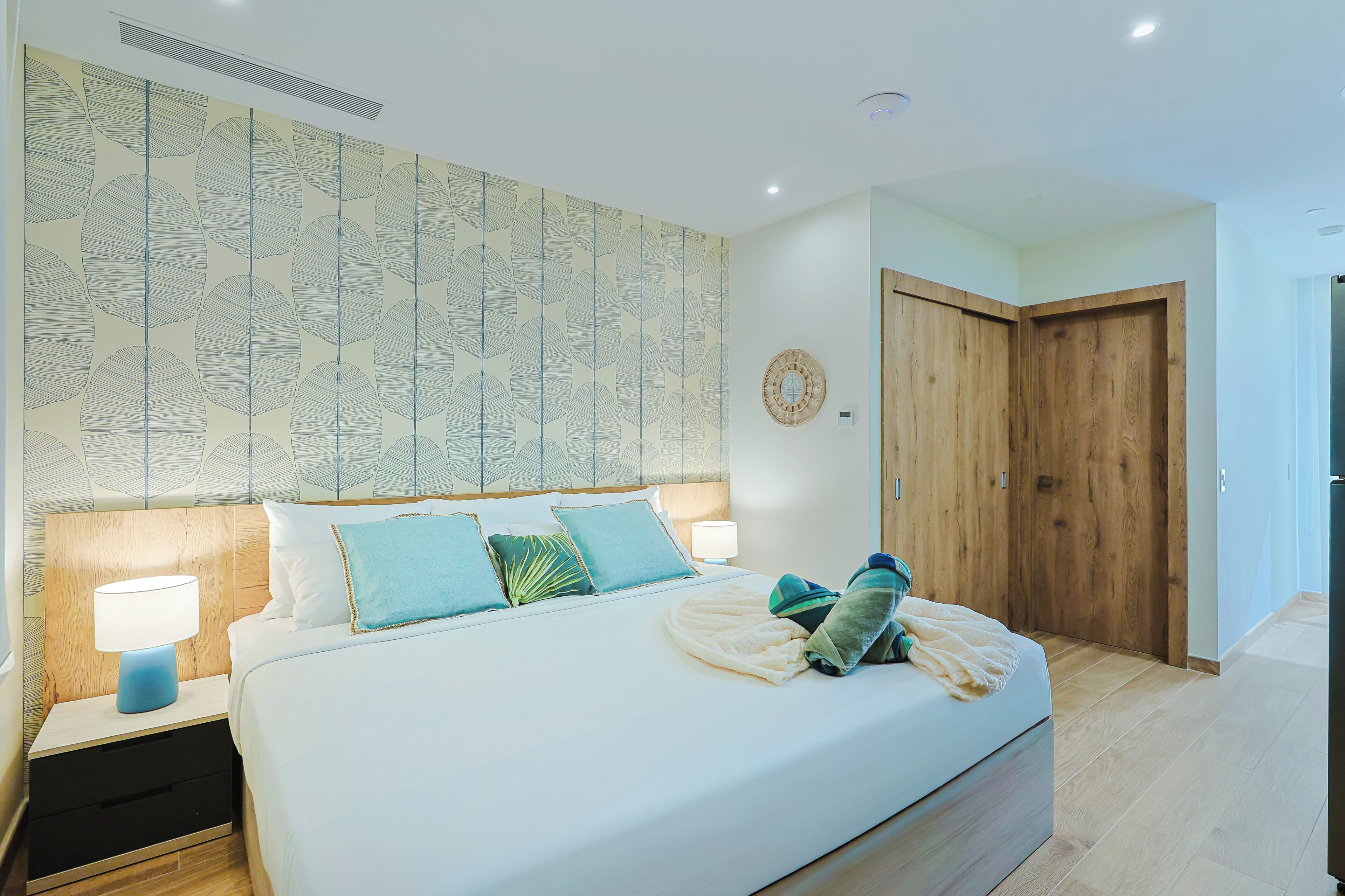 A bedroom with a large bed, bedside tables, a wooden door, and a patterned wall.