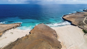 A coastal landscape with a sandy beach and rocky cliffs overlooking the ocean. - Bonsai Studio-Nature 204 (Noord)