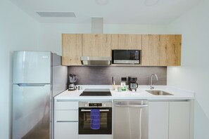 A modern kitchen with a built-in microwave, refrigerator, and dishwasher. - Bonsai Studio-Sunset 309 (Noord)