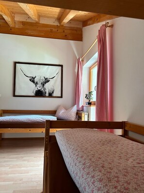 A bedroom with two wooden bunk beds, a framed animal print on the wall, and a window with pink curtains. - Apartment 'Zum Rießacker' with Mountain View and Wi-Fi (Garmisch-Partenkirchen)