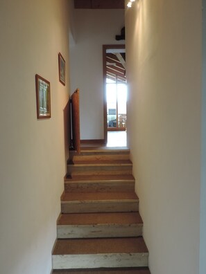 A staircase with wooden steps leading to a bright room with a window. - Apartment 'Zum Rießacker' with Mountain View and Wi-Fi (Garmisch-Partenkirchen)