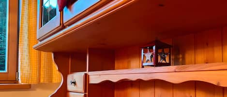 A wooden cabinet with drawers and a shelf, a window with curtains, and a star-shaped decoration.