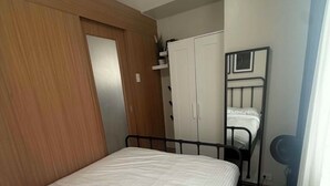 Un dormitorio con cama, armario y espejo.