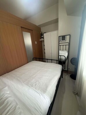 Ein Schlafzimmer mit Bett, Kleiderschrank und Spiegel.