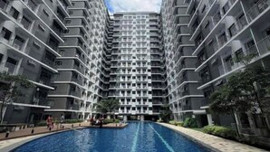 Un edificio residencial alto con una piscina central rodeada por un sendero empedrado.