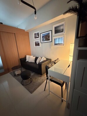 Ein modernes Wohnzimmer mit einer Couch, einem Esstisch und einem Couchtisch. An den Wänden hängen gerahmte Bilder und auf dem Tisch steht eine Lampe.