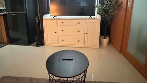 Una sala de estar con televisor, un aparador, una mesita y una planta en maceta.