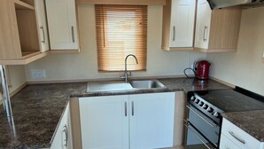 A compact kitchen with a sink, stove, and cabinets. - Bwlchgwyn Caravan, Aberdaron (Pwllheli)