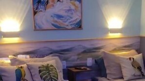 A hotel room with two beds, a painting on the wall, and wall-mounted lamps. - Fite Suítes (Fernando de Noronha)