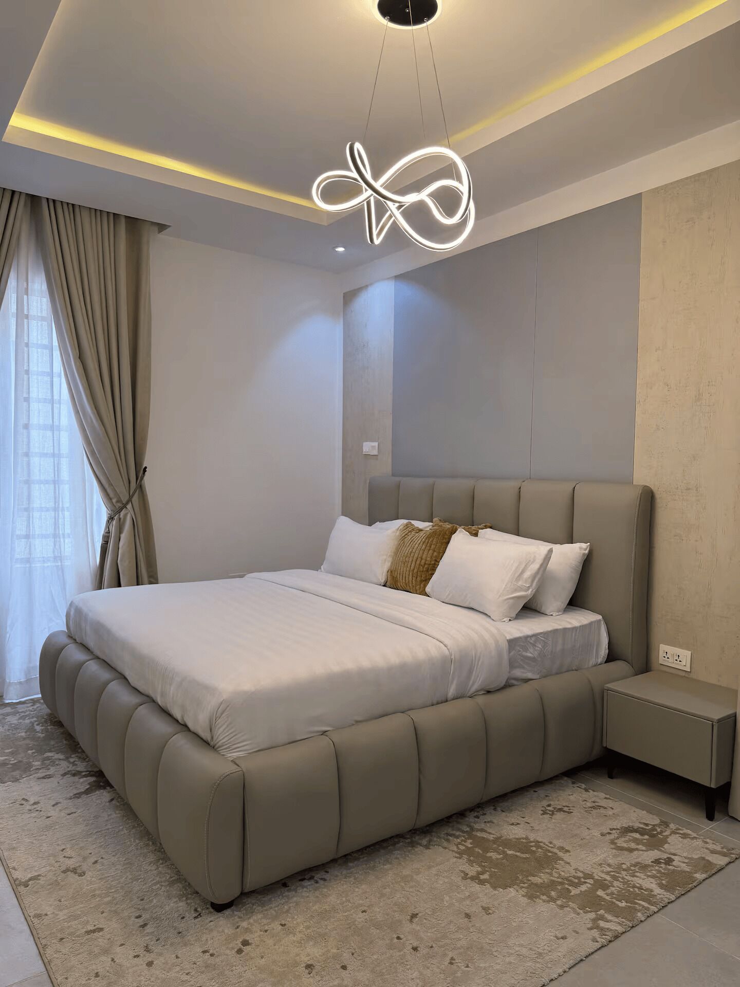 Une chambre moderne avec un grand lit, une table de chevet et un luminaire au plafond original.